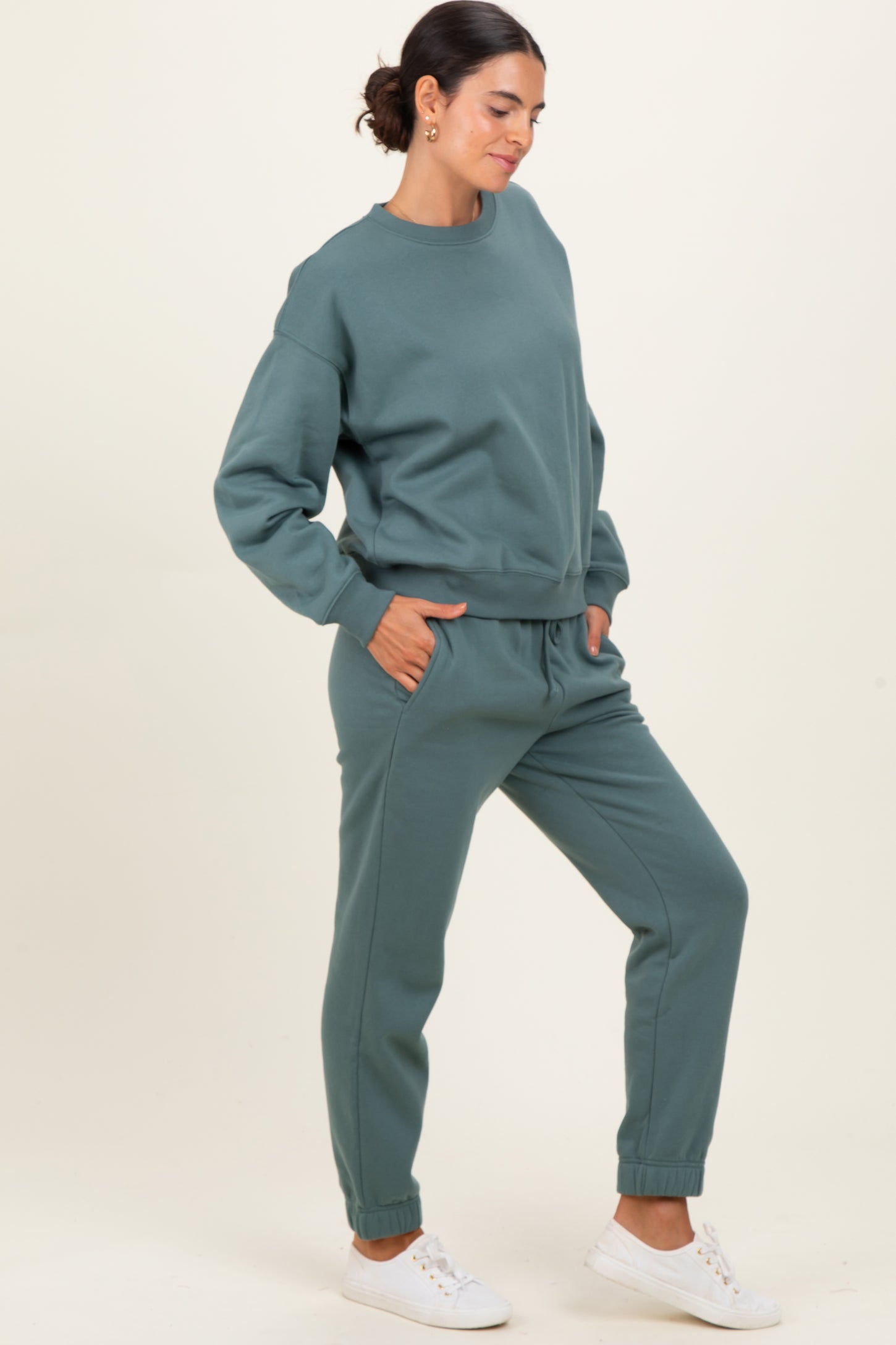 woman wearing a teal sweatshirt and matching sweatpants with side pockets and cuffed ankles