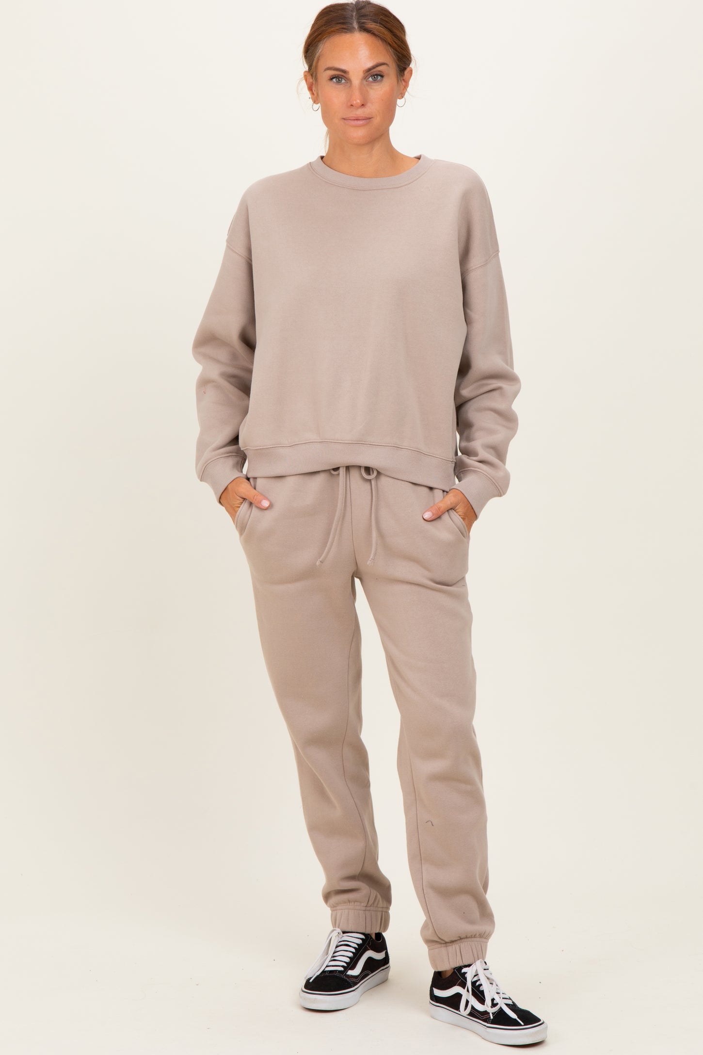 woman wearing a beige oversized sweatshirt and matching sweatpants with pockets and elastic cuffs