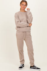 woman wearing a beige oversized sweatshirt and matching joggers, styled with black sneakers