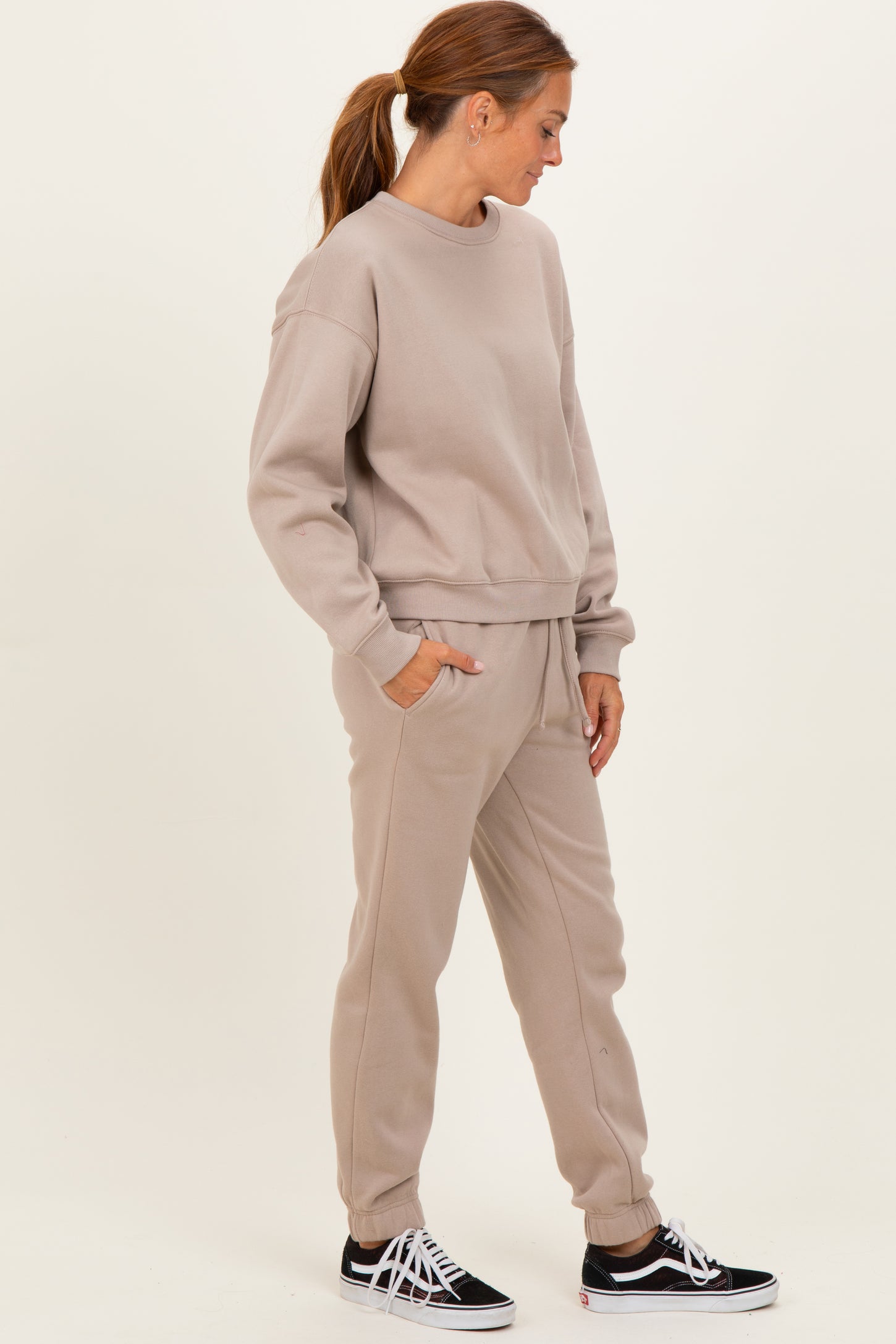 woman wearing a taupe oversized sweatshirt and matching joggers with side pockets and a relaxed fit