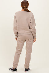 woman wearing a beige sweatshirt and matching sweatpants, seen from the back, casual loungewear style