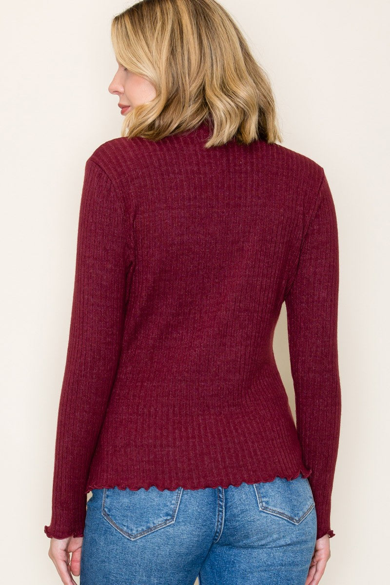 woman wearing a maroon ribbed long sleeve top with a scalloped hem and back view, paired with blue denim jeans