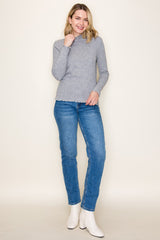 woman wearing a gray ribbed long sleeve top with a scalloped hem and blue straight-leg jeans, paired with white ankle boots