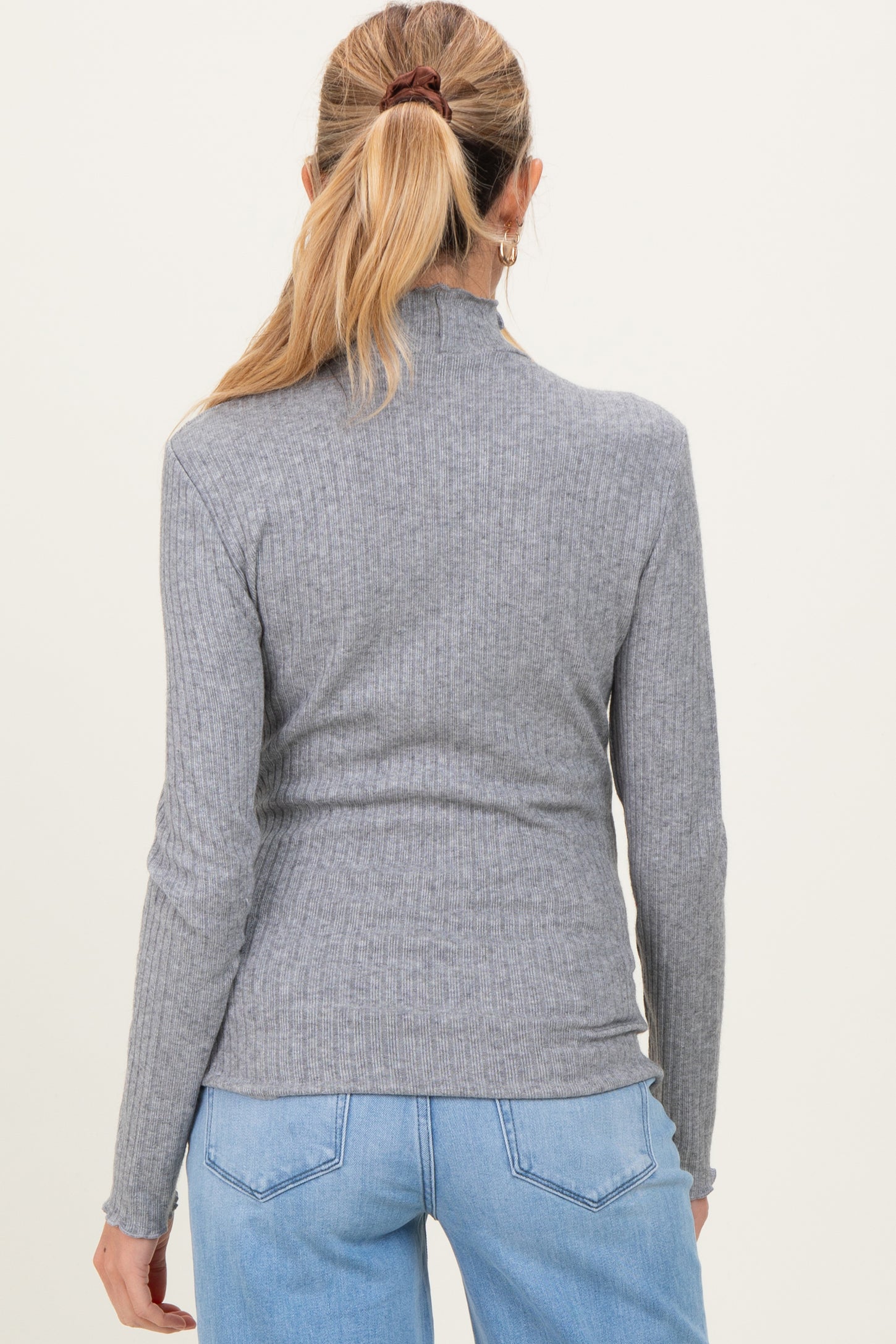 woman wearing a grey ribbed maternity turtleneck top, viewed from the back with long sleeves and a fitted style