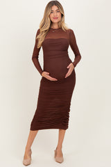 woman wearing a brown long sleeve maternity dress with ruching and holding her baby bump