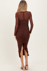 woman wearing a brown long sleeve ruched maternity dress with a thigh-high slit, showing a baby bump at the back