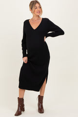woman wearing a black maternity dress with a v-neck and side slits, showing her baby bump and paired with brown ankle boots