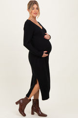woman wearing a black maternity sweater dress with a v-neck, side slits, and holding her baby bump
