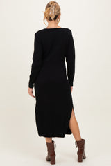 woman wearing a black maternity sweater dress with side slits and long sleeves, styled with brown heeled boots