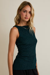 woman wearing a dark green sleeveless ruched top with sparkly details