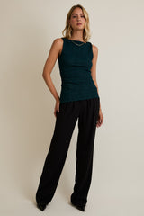 woman wearing a teal sparkly sleeveless top and black wide-leg pants