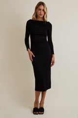 woman wearing a black long sleeve fitted midi dress with a draped neckline and styled with black slide sandals