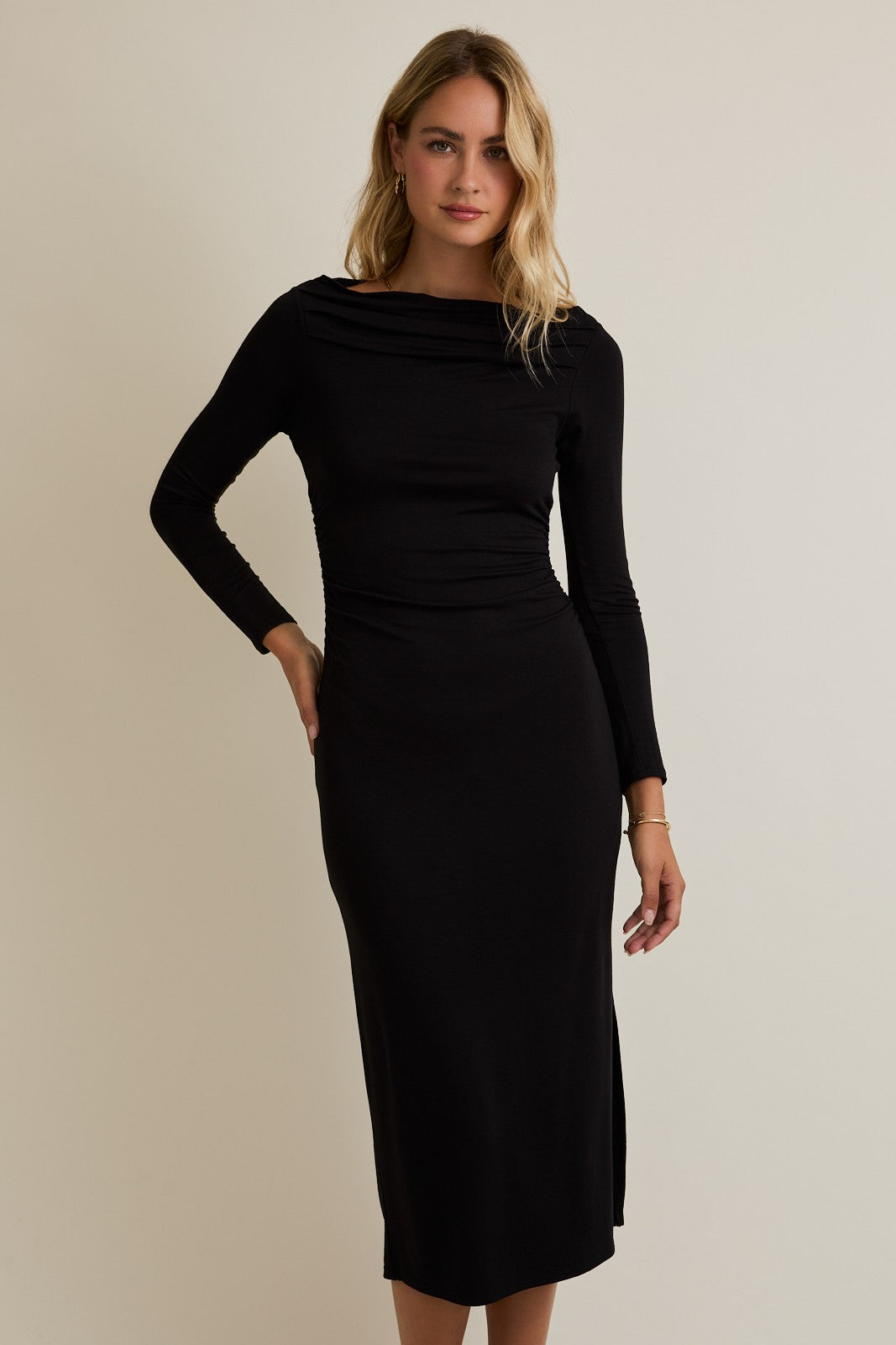 woman wearing a black long sleeve fitted dress with a high neckline and side slit