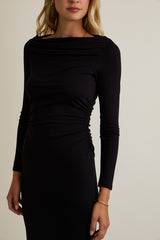 woman wearing a black long sleeve dress with gathered side detailing and a boat neckline
