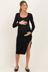 woman wearing a black long sleeve maternity dress with a side slit and holding her baby bump
