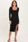 woman wearing a black ribbed long sleeve midi dress with a side slit and strappy heels