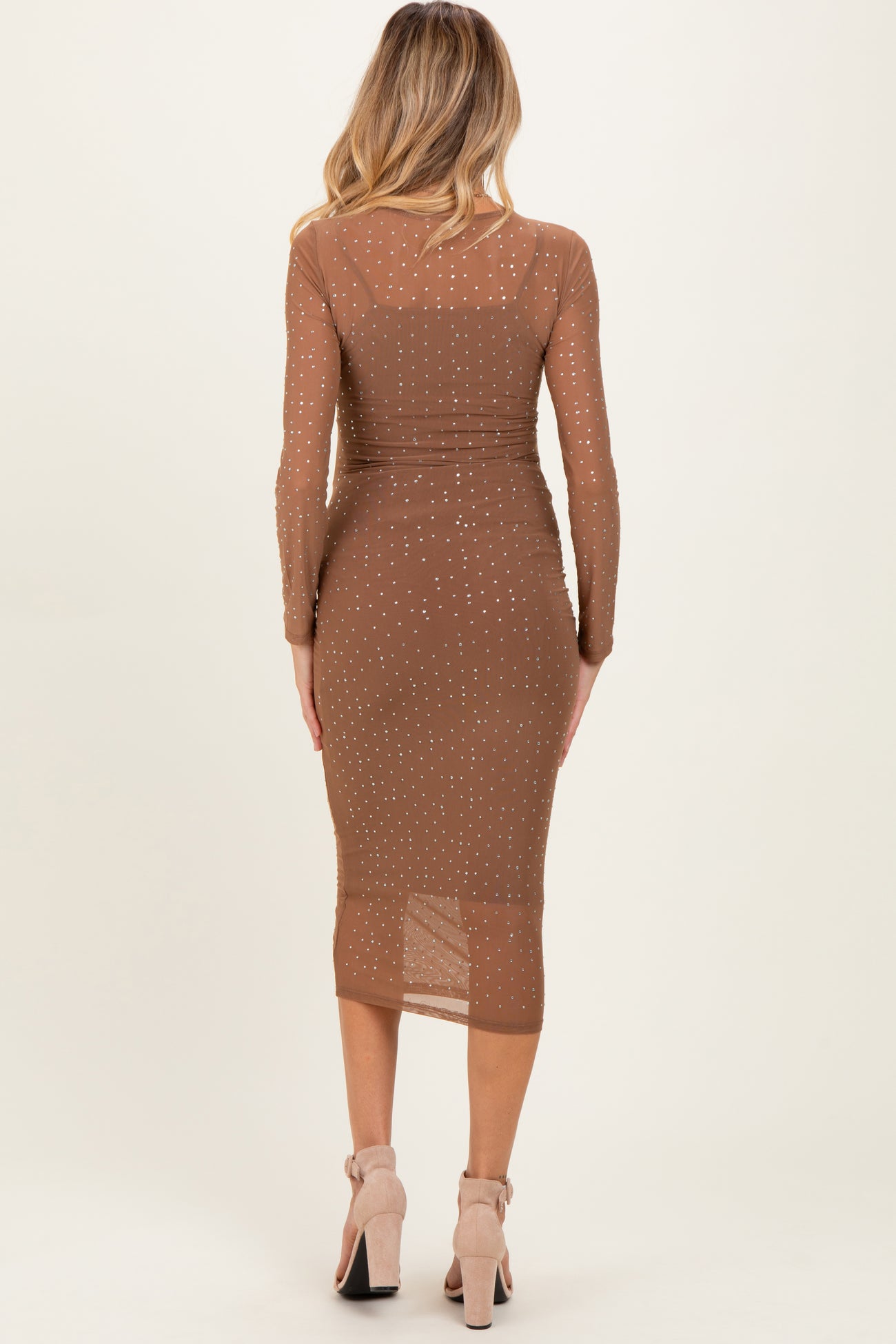 woman wearing a brown long sleeve maternity dress with sheer detailing and embellishments, close-fitting style