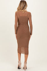 woman wearing a brown long sleeve maternity dress with sheer detailing and embellishments, close-fitting style