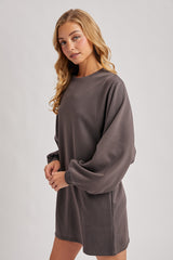 woman wearing a dark gray oversized sweatshirt dress with balloon sleeves and side pockets