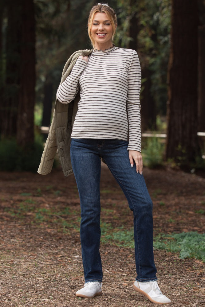 woman wearing a striped long sleeve maternity top with a round neckline and blue maternity jeans, standing outdoors