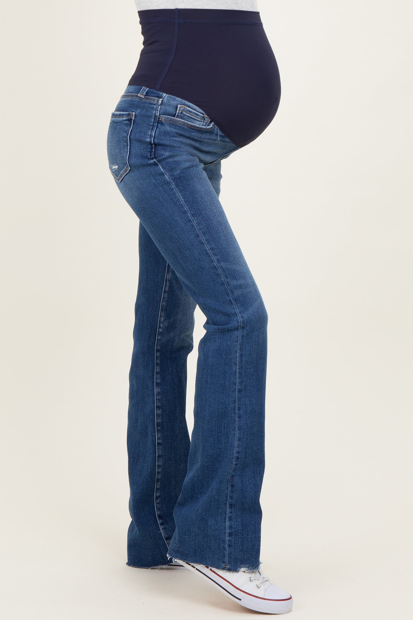 woman wearing dark wash maternity flare jeans with a supportive belly panel and showing her baby bump