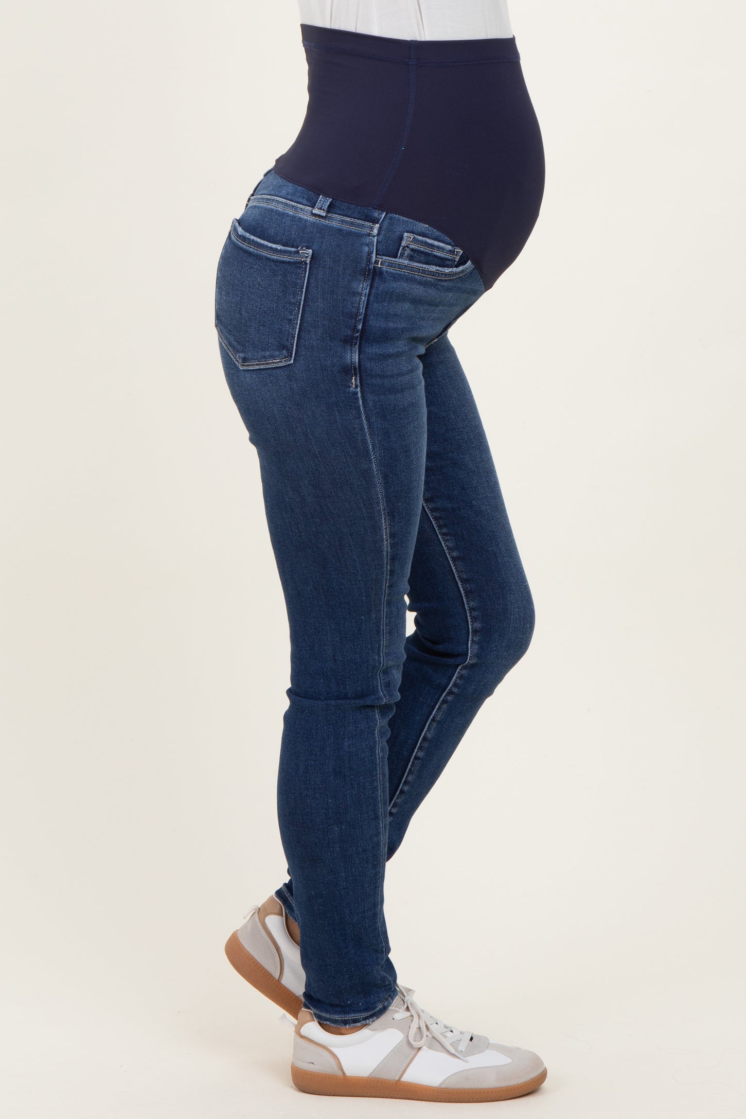woman wearing dark blue maternity skinny jeans with a high waistband, showing her baby bump