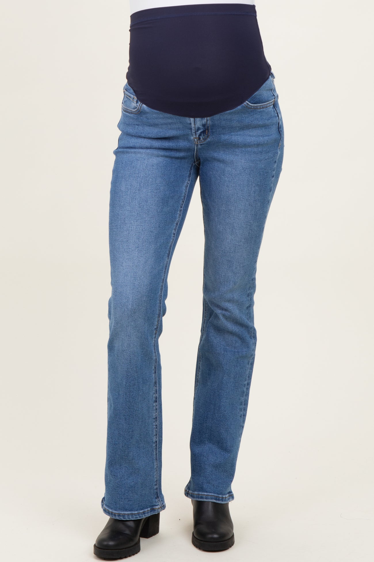 woman wearing a pair of blue maternity bootcut jeans with a dark waistband, showing a baby bump
