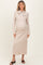 woman wearing a light beige maternity sweater dress with a bow tie detail and long sleeves, showing her baby bump