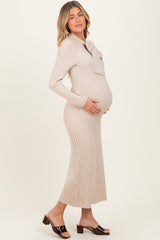 woman wearing a beige ribbed maternity dress with a bow tie detail and holding her baby bump