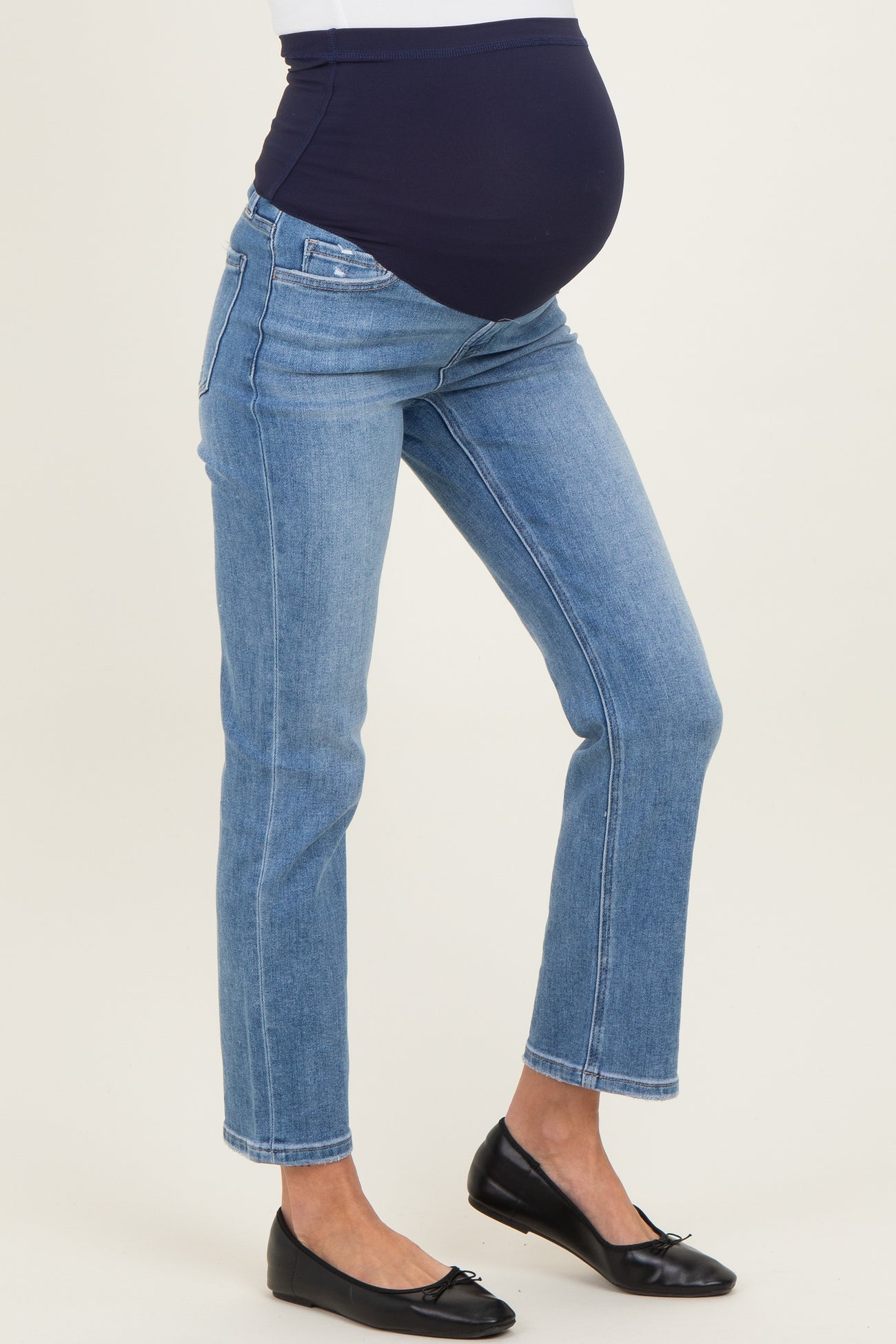 woman wearing blue maternity jeans with an over-the-bump panel and a visible baby bump