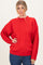 woman wearing a red oversized sweater with cable knit sleeves and a relaxed fit, paired with blue jeans