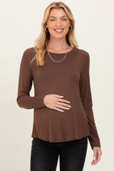 woman wearing a brown long sleeve maternity top and holding her baby bump