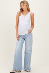 woman wearing a white ribbed maternity tank top and light blue wide-leg maternity jeans, showcasing her baby bump