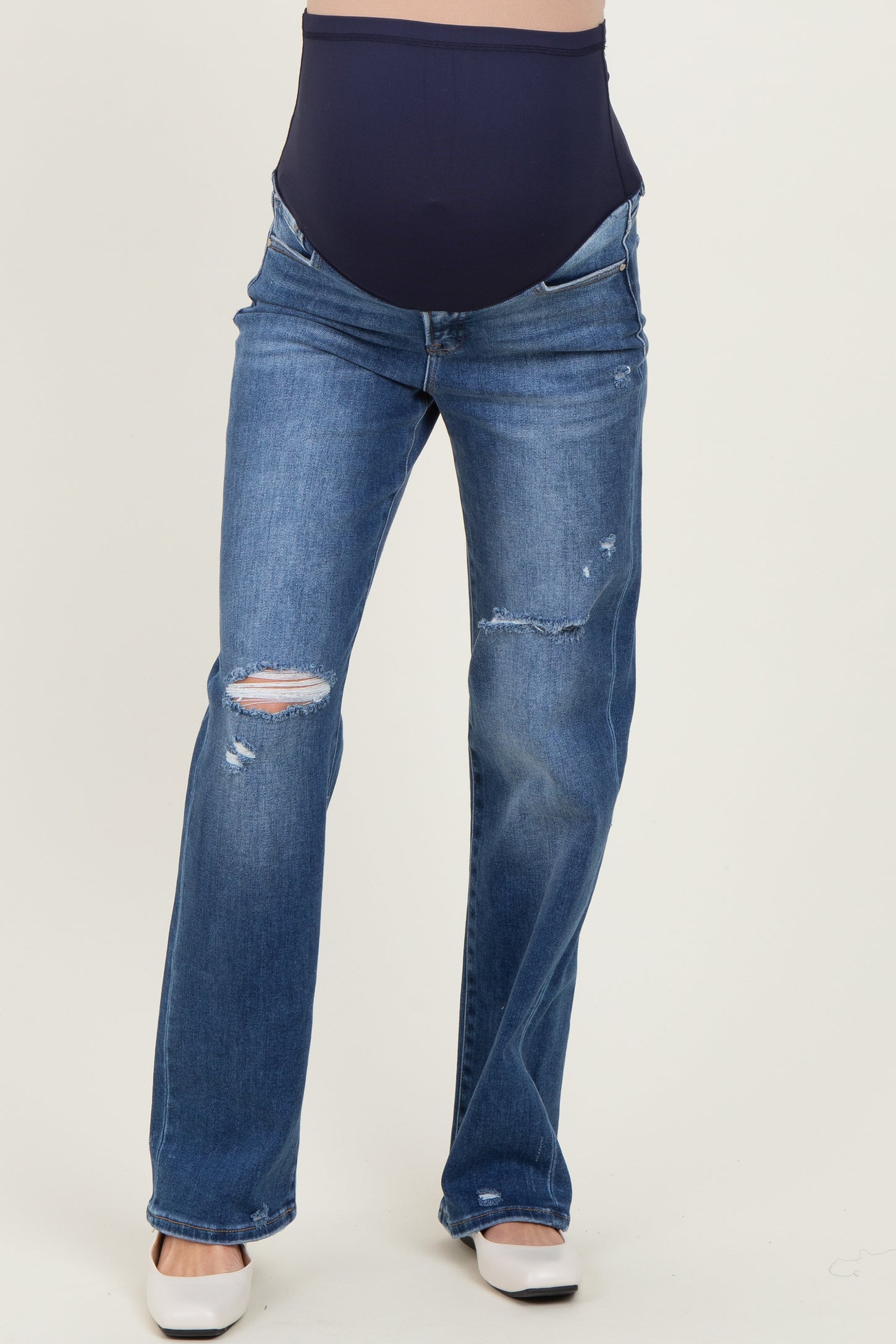 woman wearing distressed blue maternity jeans with a navy belly panel and flared leg style