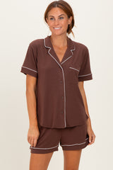 woman wearing a brown short sleeve pajama set with white piping and a pocket
