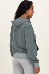woman wearing a green maternity hoodie with a relaxed fit and hood, side view showing her baby bump