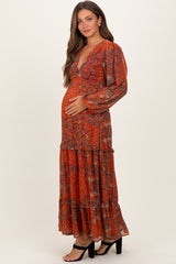 woman wearing a rust floral print maternity dress with a tiered skirt and a visible baby bump