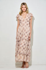 woman wearing a long floral maxi dress with ruffled sleeves and a tiered skirt in soft pastel colors