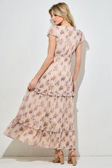 woman wearing a floral patterned maxi dress with tiered ruffles and short sleeves, viewed from the back