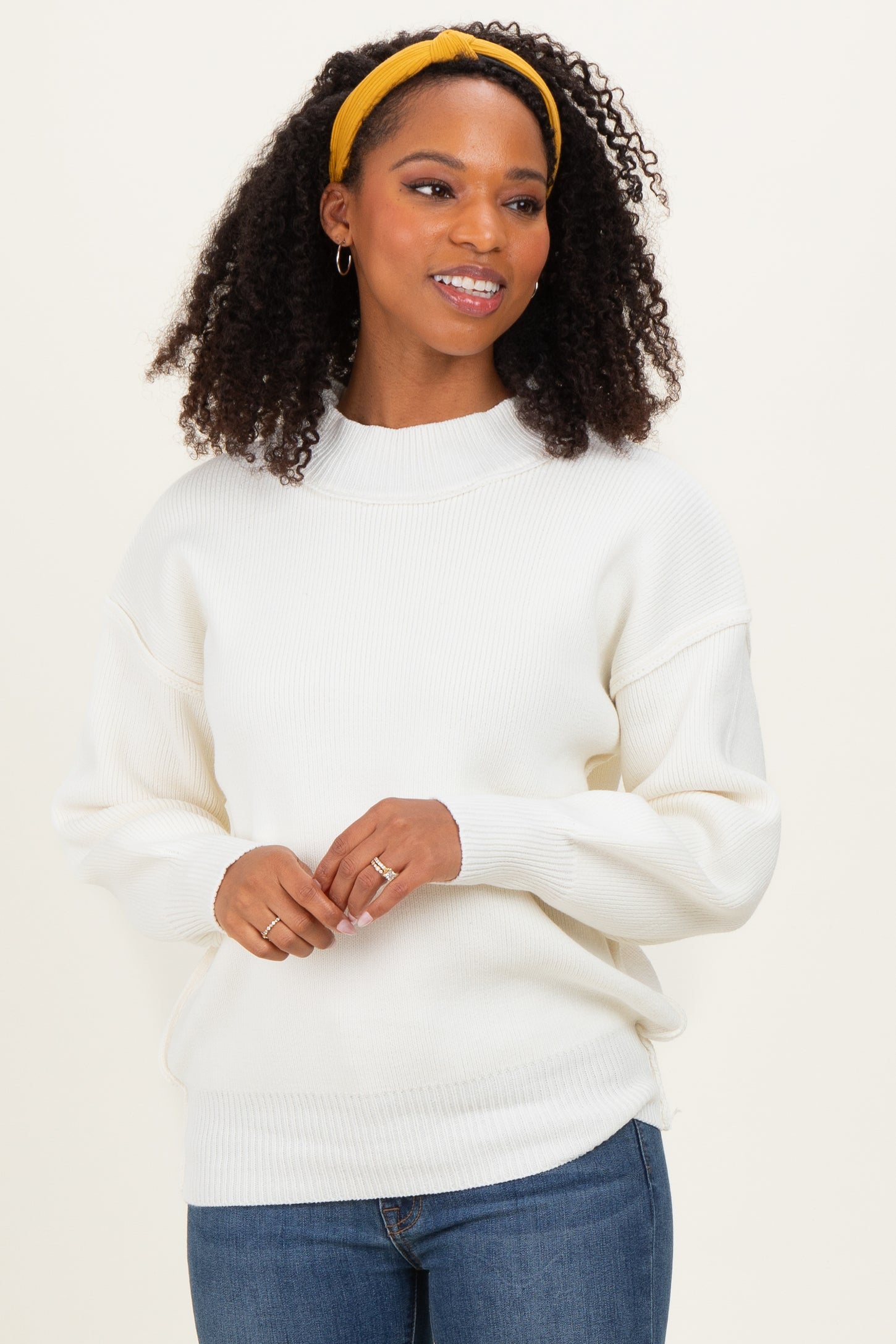 woman wearing a white ribbed sweater with a mock neck and balloon sleeves, styled with a yellow headband