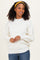 woman wearing a white ribbed sweater with a mock neck and balloon sleeves, styled with a yellow headband