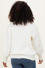 woman wearing a cozy white oversized sweater with balloon sleeves, seen from the back with curly hair and blue jeans