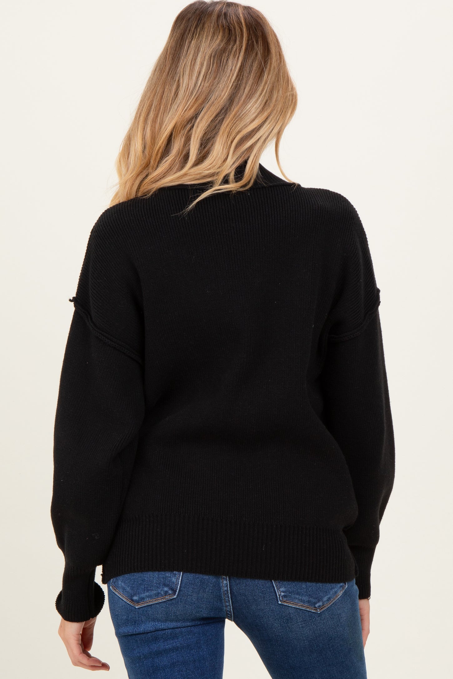 woman wearing a black oversized maternity sweater with a relaxed fit, seen from the back