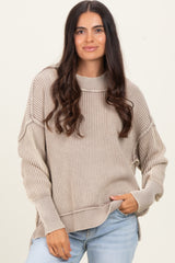 woman wearing a beige ribbed sweater with side slits and a relaxed fit, paired with light blue jeans