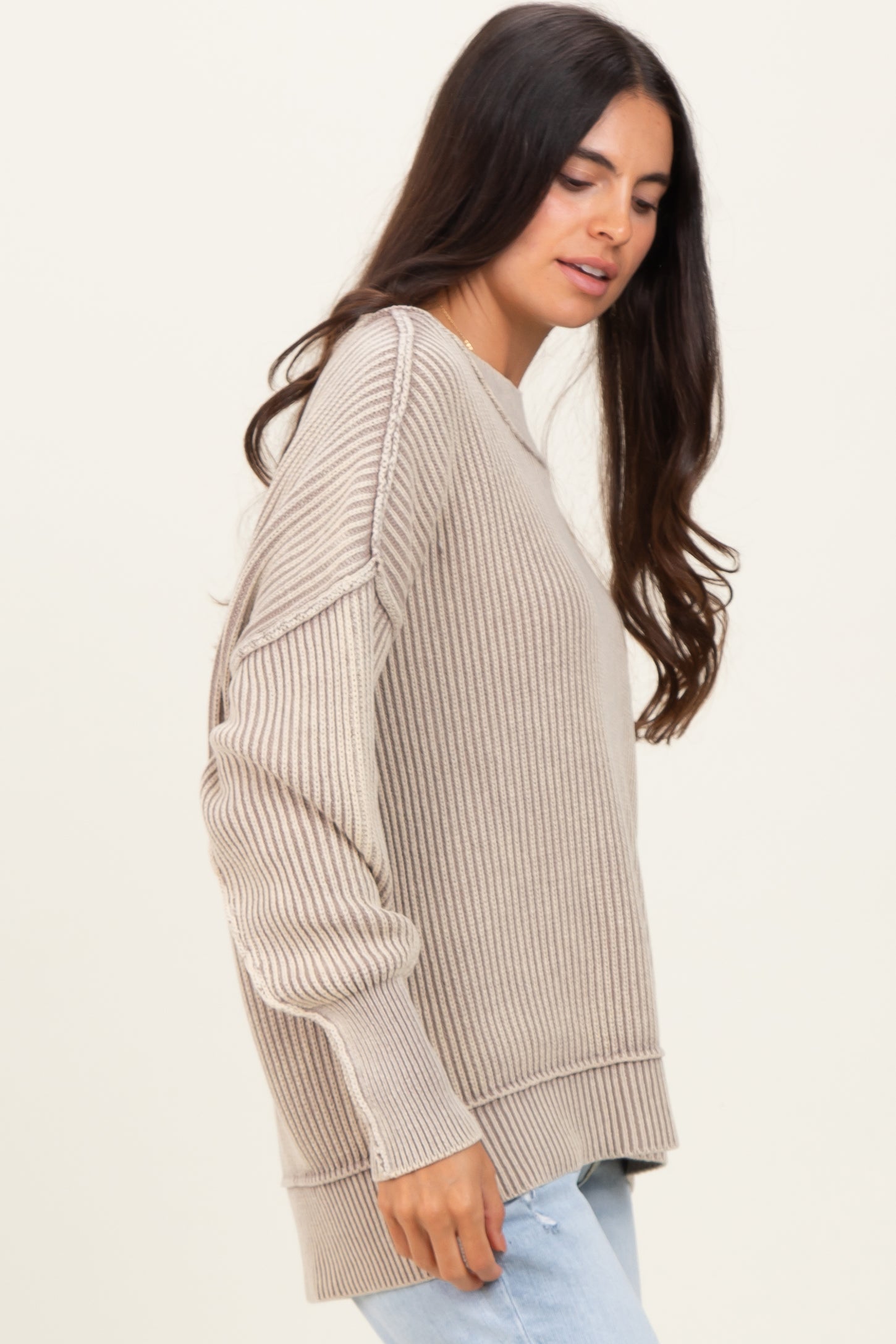 woman wearing a light beige ribbed sweater with long sleeves and side slit detailing