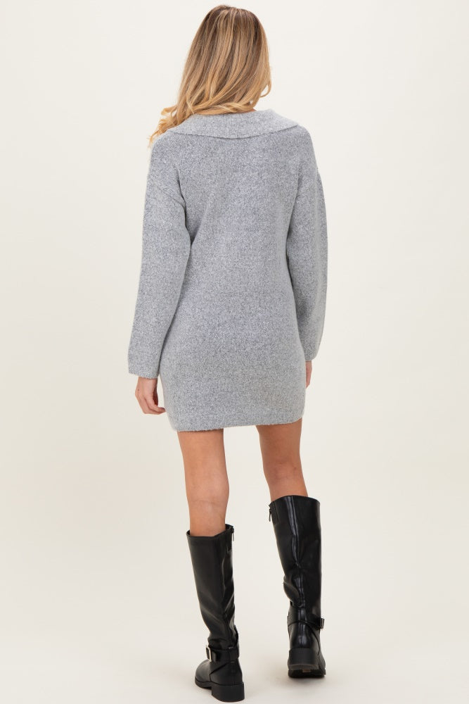 woman wearing a grey maternity sweater dress with long sleeves and a relaxed fit, styled with knee-high black boots