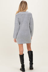 woman wearing a grey maternity sweater dress with long sleeves and a relaxed fit, styled with knee-high black boots