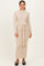 woman wearing a light beige long sleeve knit dress with a tied waist and a straight fit, standing against a neutral background
