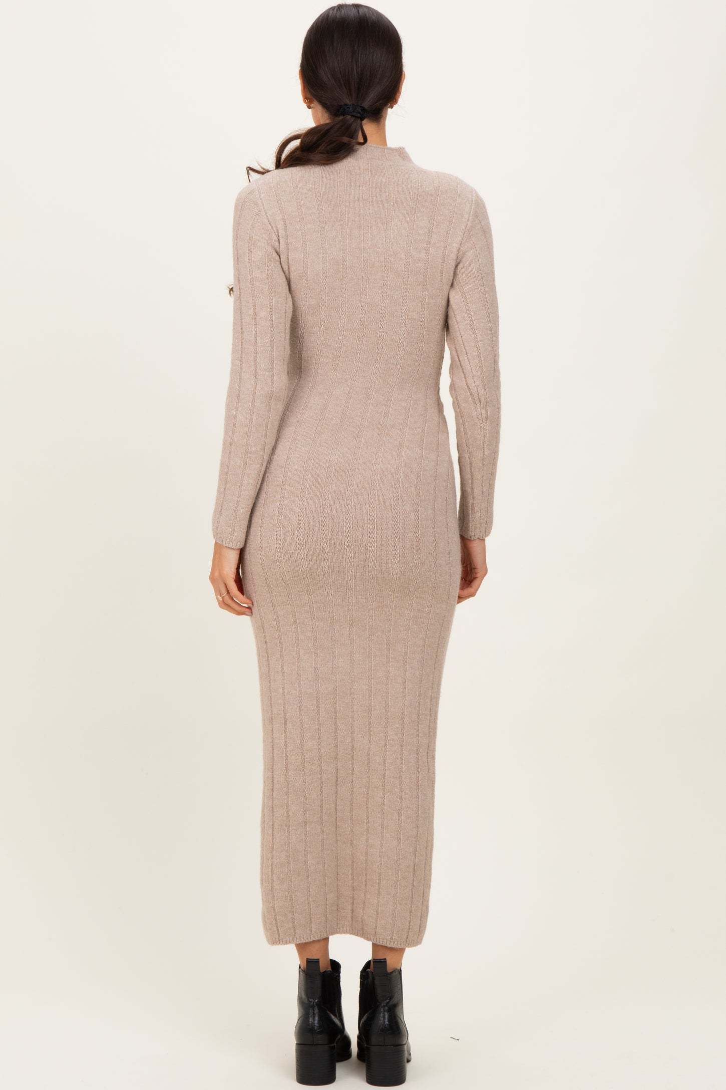 woman wearing a long beige ribbed knit dress with long sleeves and a fitted silhouette from the back