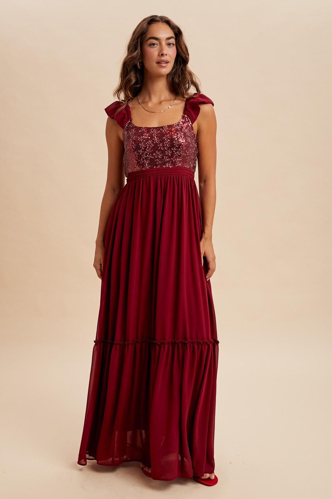 woman wearing a burgundy maxi dress with sequined bodice and ruffled straps